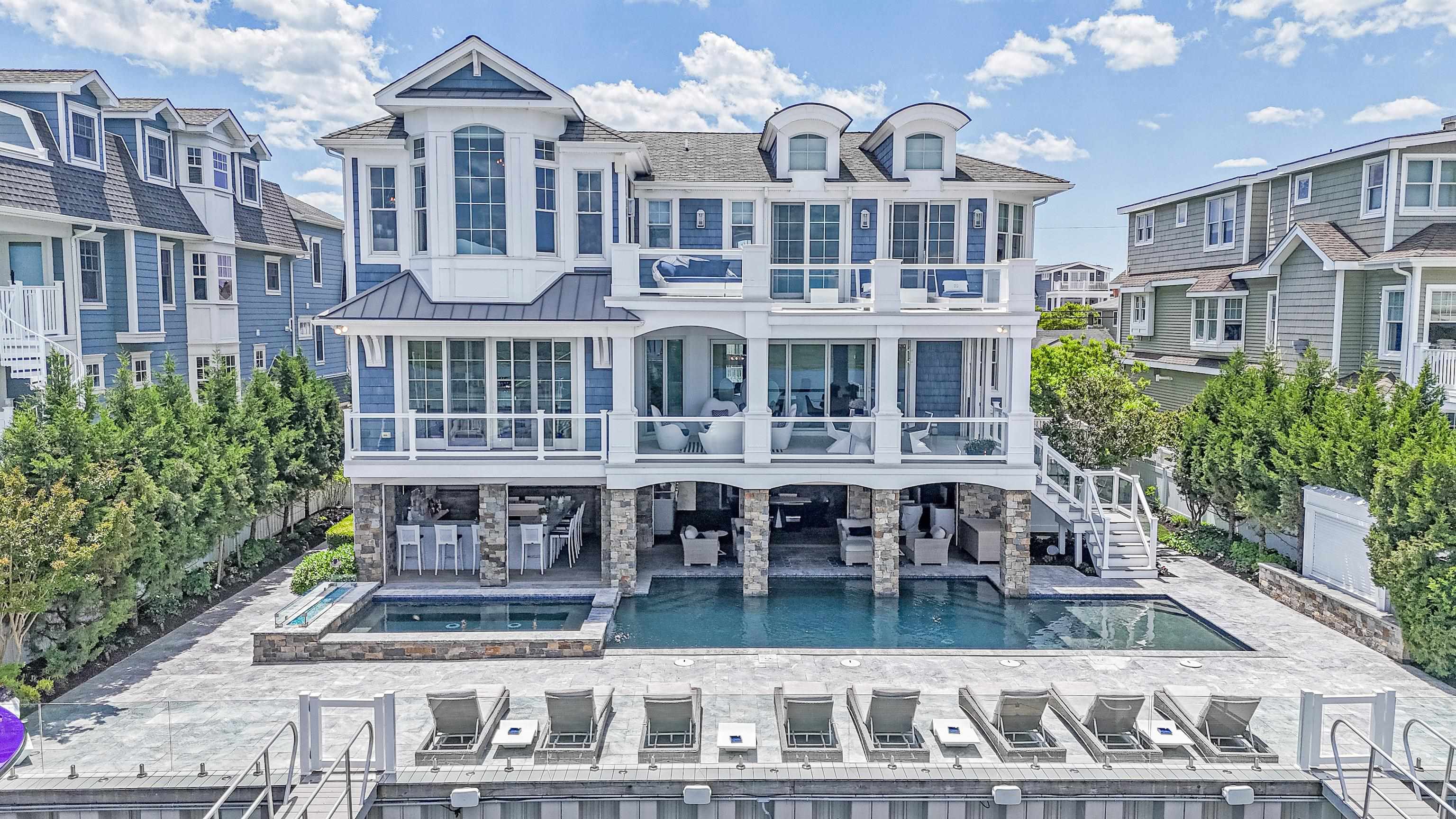 Extraordinarily unique BAY FRONT custom home situated on two buildable waterfront lots offering astounding, unobstructed views looking north with the added convenience of being able to walk to town. Designed with entertaining being the primary focus, this home has every amenity certain to make your shore experience a memorable one. The classic Nantucket Seaport exterior belies the beautiful, contemporary design found inside the home the minute you cross the threshold and are greeted with a beautiful mosaic tiled wall, elliptical staircase with clear treads, stainless steel railing and a fabulous blown glass chandelier. There are six generous bedrooms, each with custom tiled baths and a powder room servicing the great room. The second-floor main living area has an expansive, waterfront great room designed to take advantage of wonderful water vistas. The kitchen is a chef’s dream with ultra high-end appliances such as Gaggenau, Subzero, two Miele dishwashers and full pantry. The dining area has fully retractable doors opening to a covered waterfront deck. The spacious living room has a ceiling full of artful blown glass lighting fixtures and a mosaic wall sure to be a topic of conversation. Adjacent to the living room is a fabulous, large U-shaped bar with flat panel tv, ice machine, two beverage fridges, wine fridge, stone top with color changing fiber optic under lighting and a transparent glass floor with calming river stones. The master bedroom is waterfront with large deck, his and hers bathrooms sharing a gorgeous, oversized shower, two fabulous walk-in closets, gym and second laundry. The pool area exceeds anything you have seen on the island. Just a few of the amenities are an oversized pool with custom finish, water feature, sun shelf, attached ten person plus spa, fiber optic lighting, dramatic fire pit, high end glass panel safety fence that does not obstruct your water view and spacious pool decking. The cabana with custom grill and conversation areas will take care your breath away. For the boater, there are four large slips and a 30,000-pound lift. For the sports car enthusiast, there is a three-car attached garage. Other features include beautiful wood look tile floors throughout, four stop elevator, Control Four A/V, lighting and security system, auto hurricane shutters, extraordinary sound system with speakers and cameras everywhere, system controlled colored lighting throughout, multi zoned HVAC, commercial and residential ice machines and much more. In addition, the home is sold beautifully, designer furnished that perfectly complements the unique contemporary feel of the home.
