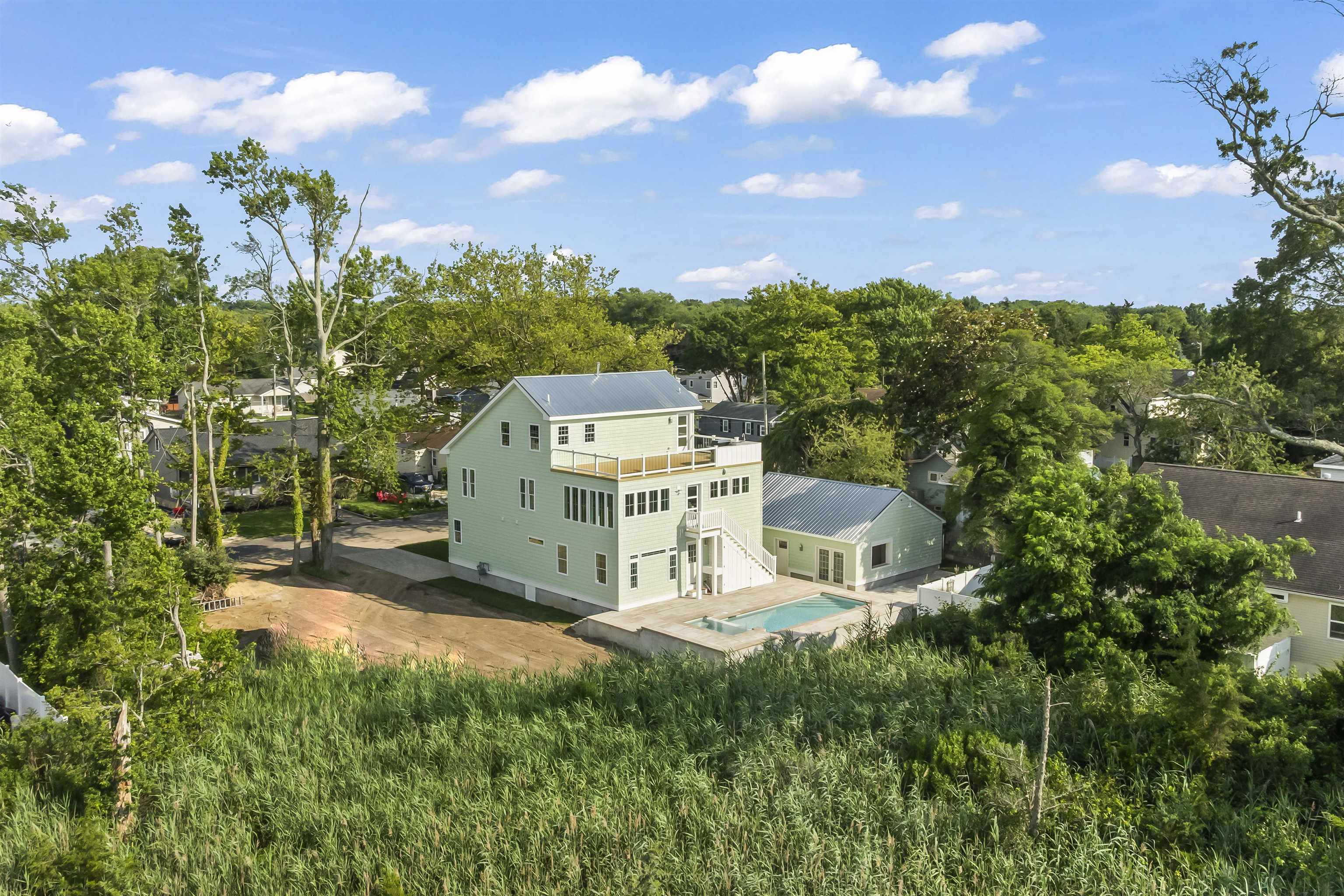 Coastal elegance meets modern design in this Custom New Construction Bayview Retreat, perfectly crafted for luxury living and effortless entertaining. This stunning home offers breathtaking views of the Delaware Bay from all three floors. The backyard is a true showstopper, featuring a custom pool with integrated hot tub spa, surrounded by pavers and enhanced by a stylish poolside cabana, your own private escape. The first floor features all four bedrooms, thoughtfully arranged for comfort and privacy. The primary suite is located at the rear of the home with a peaceful view of the pool. This bedroom includes a spacious walk-in closet and a luxurious en suite bathroom featuring a massive custom tile shower with a freestanding soaking tub set elegantly at the rear, creating a true spa-like experience. On the same side in the front is the second bedroom with its very own private en suite bathroom. On the opposite side of the home, two additional bedrooms share a spacious Jack and Jill bathroom with dual tile showers, one of which includes a soaking tub. All bathrooms throughout the home are finished with elegant tile flooring and custom tile showers, offering both style and functionality. Beautiful white oak engineered hardwood flooring runs seamlessly throughout the entire home, enhancing the cohesive and sophisticated design. The second floor is the main living space, where a bright and open layout is complemented by the continuing white oak engineered hardwood floors. At the heart of this level is a custom kitchen with a large center island, quartz countertops, and a professional-grade Kucht oven with a custom hood—perfect for gathering and entertaining. A convenient powder room completes this floor, adding to the home's thoughtful design. Upstairs, the third floor opens to a massive storage area and a rooftop deck built for entertaining. Enjoy incredible views of the bay from this elevated perch, complete with a built-in grill, sink, and beverage refrigerator. Additional features include an outdoor shower, an expansive paver driveway that leads to a detached two-car garage, a separate paver parking space, a charming natural stone walkway, a durable galvanized metal roof, an on-demand hot water system, and a sprinkler system to maintain the lush, vibrant landscaping. Just a short distance from the water’s edge, this exceptional property blends luxury, functionality, and breathtaking scenery—offering the ultimate coastal lifestyle in one of the most desirable areas along the Jersey Shore. This stunning residence is proudly known as The Mint Chip House. Schedule an appointment today to tour this beautiful home and experience everything it has to offer.