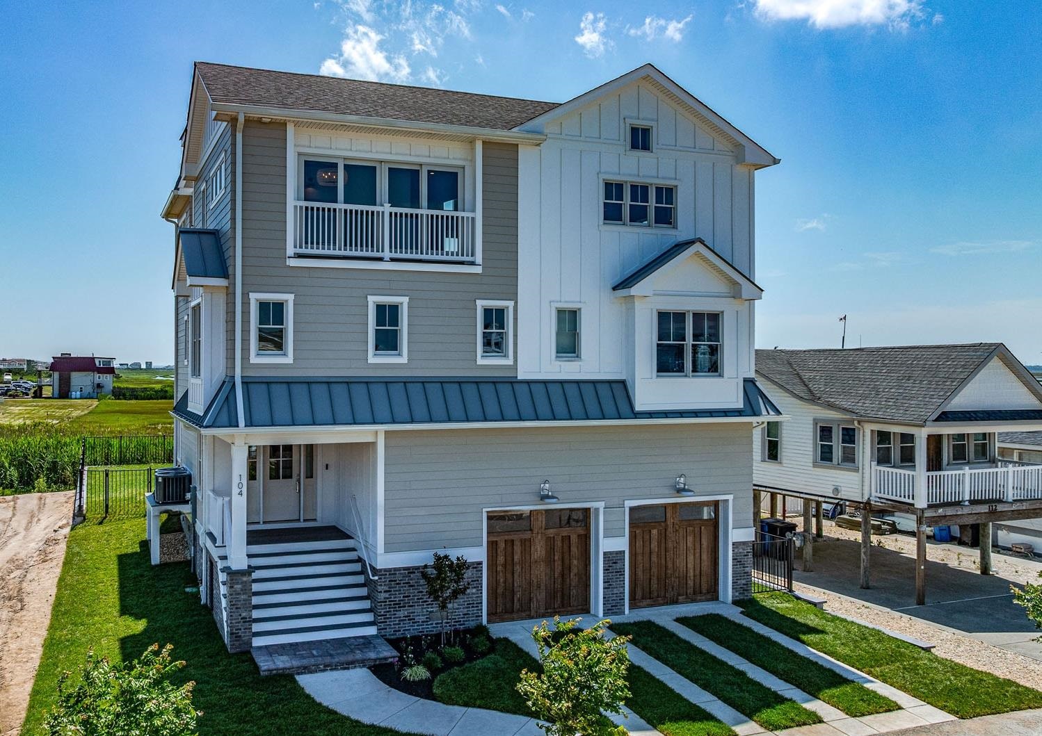 This single-family custom built home offers a level of island luxury that rarely becomes available in Strathmere. The stunning exterior is wrapped in James Hardie Plank lap along with board and batten siding and a standing seam metal roofing. Upon entering the foyer you will notice the wide plank engineered hardwood flooring which flows throughout the entire home. The lower-level recreation room features a wet bar with beverage refrigerator, powder room, and direct access to an oversized paver patio with prime Southern exposure. The middle level houses four well-appointed bedrooms all with en suites. The spacious primary suite sits closest to the water and is highlighted by the shiplap accent wall, private deck, and luxurious marble tiled bath. Sleeping is maximized thanks to the custom built in bunk room featuring 4 beds all with their own personal reading lights & charging nooks. A laundry room with double stacked washers & dryers further enhances the ability to comfortably house multiple groups of people. On the top level you will find the main living, den, dining, and kitchen spaces seamlessly blended.  The custom kitchen includes a stunning mitered drop edge quartz counter, GE Monogram appliances, double dishwashers, ample pantry, and abundant storage tucked behind custom cabinetry. Adjacent to the kitchen is the living room with gas fireplace flanked in Pennsylvania bluestone. The living area is located directly under a striking vaulted ceiling highlighted by exposed Oak beams & includes a four panel Andersen glider with transom window flooding the space with natural light. A proper dining room with a wet bar with wine cooler, coffered ceiling, custom bookcase, & Juliet balcony all combine to provide the ideal space for hosting large dinner parties. A sizeable den with a wall of oversized windows overlooking the wetlands completes this level and offers the flexibility to serve additional sleeping needs, as a library, playroom, exercise space, or other. Heading up a final flight of stairs the Polyurea roof top deck affords utmost privacy coupled with sweeping water views of the ocean, bay, and preserved wetlands that frame the property. No details were overlooked in the creation of this residence as evidenced by the Origin Acoustics distributed audio system, four-stop elevator, underground utilities, custom built-in closets, security cameras &alarm system, two on-demand water heaters, irrigation system & more. 104 Prescott is the perfect blend of thoughtful design coupled with expert craftsmanship to produce a truly stunning product.