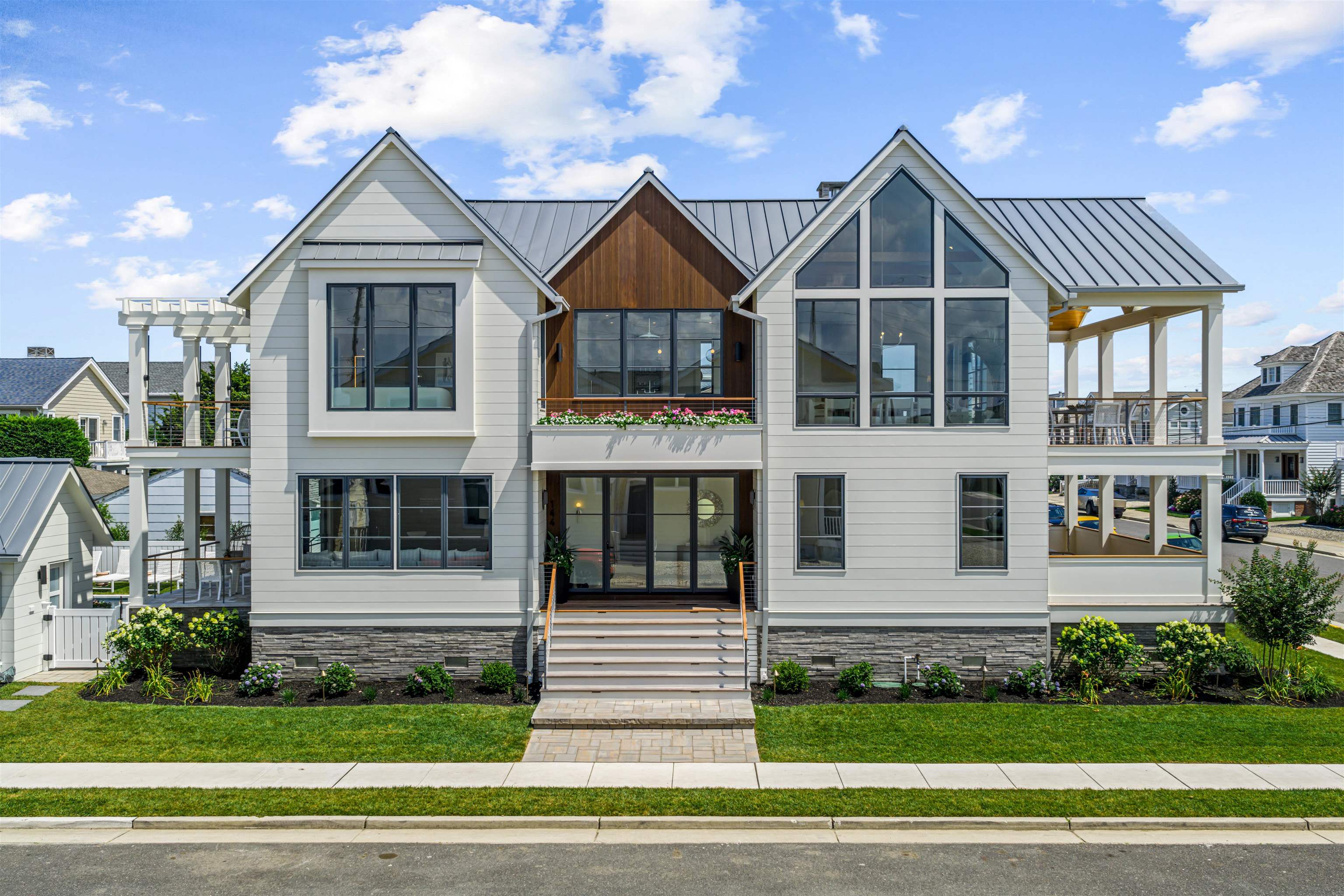 Introducing a brand-new, fully custom estate in Stone Harbor’s highly coveted Pennsylvania Avenue neighborhood. Brought to you by Wolstenholme Associates and WA Interiors in collaboration with McLaughlin Construction, this 5-bedroom, 5.5-bath home is offered fully designer-furnished and accessorized with a refined blend of custom and high-end selections.    The exterior finishes were selected with sustainability, aesthetics, and longevity in mind. The cladding includes a mix of Acre ship lap siding with 10” exposure (made from upcycled rice hulls) and reSAWN’s MYNAH thermally modified radiata pine. A standing seam metal roof in a weathered zinc finish carries a 50-year warranty, while Marvin windows and doors in a gunmetal finish tie seamlessly together. All decks are finished in Ipe decking and stainless-steel cable railings capped in Ipe. The pool area is finished with Marmiro sandblasted marble and a PebbleSheen plaster pool surface.   Inside, the first floor is designed for elevated entertaining and relaxed family living. The family room, accessed through an ALLI metal pocket door, includes custom built-ins by Village Handcrafted Cabinetry and a handmade Moroccan Zellige tile backsplash. Sliding glass doors open to a raised patio that overlooks the pool, seamlessly extending the living space outdoors.   A first-floor bedroom with ensuite bath located at the front of the home, offering ocean breezes and access to a spacious front deck. It features European white oak flooring and Phillip Jeffries grass cloth wallpaper. The bathroom features a Carrara marble top vanity, Indigo Seville ceramic tile, and marble mosaic floors.  The second bedroom also has opens to the front porch, and is outfitted with shiplap millwork, a custom-built-in, and two custom Spanish-made pendant lights. The bathroom features AKDO’s Sio Cubic Plaid porcelain floor tile and marble mosaic accents. A third bedroom – complete with custom bunk beds – includes its own ensuite with a honed penny round tile floor and featured millwork.   The powder room stands out with a custom floating concrete vanity, integrated concrete sink, and hand-painted Moroccan tile. Commissioned artwork by Kirby Fredendall adorns the foyer, while a fully equipped laundry room is thoughtfully placed between the bedrooms.  Upstairs, the home opens to dramatic vaulted ceilings and sweeping ocean views. Subtle details include mud-in stair lighting, concealed Sonance speakers, and a Portola Paints plaster fireplace surround. The kitchen features a large island with leathered quartzite, Bertazzoni range, Sub-Zero refrigerator, and a full coffee bar with beverage fridge and ice maker. A custom maple dining table seats ten and overlooks the expansive living room. Through multiple sliding doors, a large front deck offers additional entertaining space and breathtaking views of the 89th Street beach path and the ocean beyond.  The fourth bedroom serves as a work-from-home space, complete with queen-sized Murphy bed, custom built-ins, with an adjacent full bath. The primary suite is a tranquil retreat with custom built-ins, spa-style bath clad in Arabescato Altissimo marble throughout, and a low-iron glass shower enclosure for crystal-clear clarity. Both bedrooms open to a private rear deck with pergola, overlooking the backyard and pool.   Additional highlights include polished nickel fixtures by Kohler and wide-plank and European white oak floors. Located just one block from one of Stone Harbor’s finest beaches and only two blocks to dining and nightlife, this corner-lot home sits in one of the borough’s most desirable residential enclaves. For additional specs and amenities on this completely custom Wolstenholme Associates home, please contact the listing agent to schedule a tour.