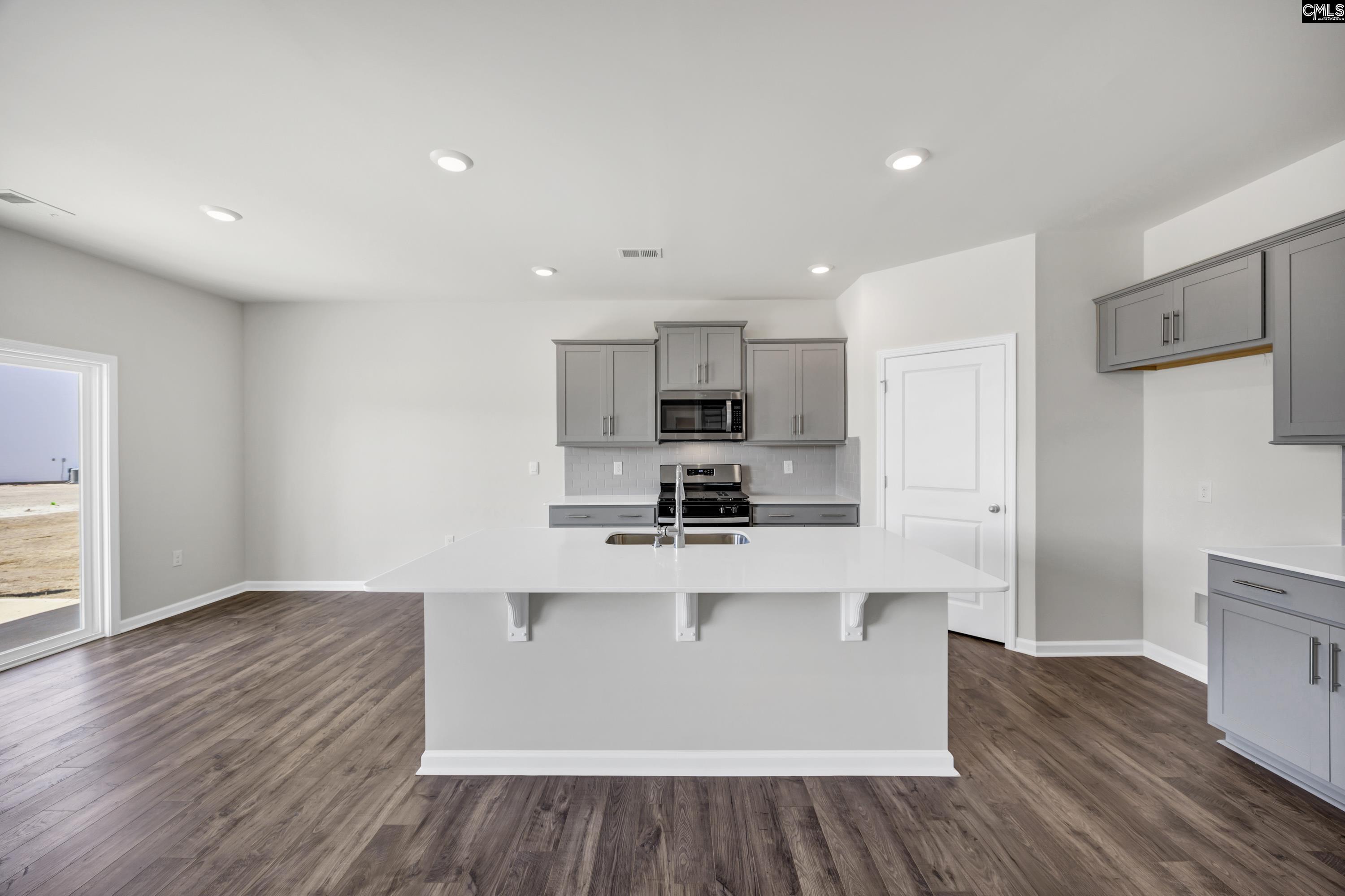 Sleek white quartz countertops, gray cabinetry, and tile backsplash