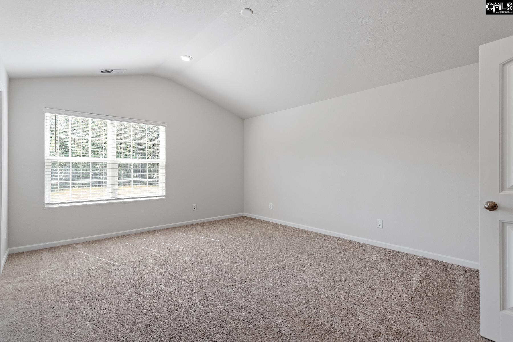 The master bedroom is spacious with a vaulted ceiling and two windows.