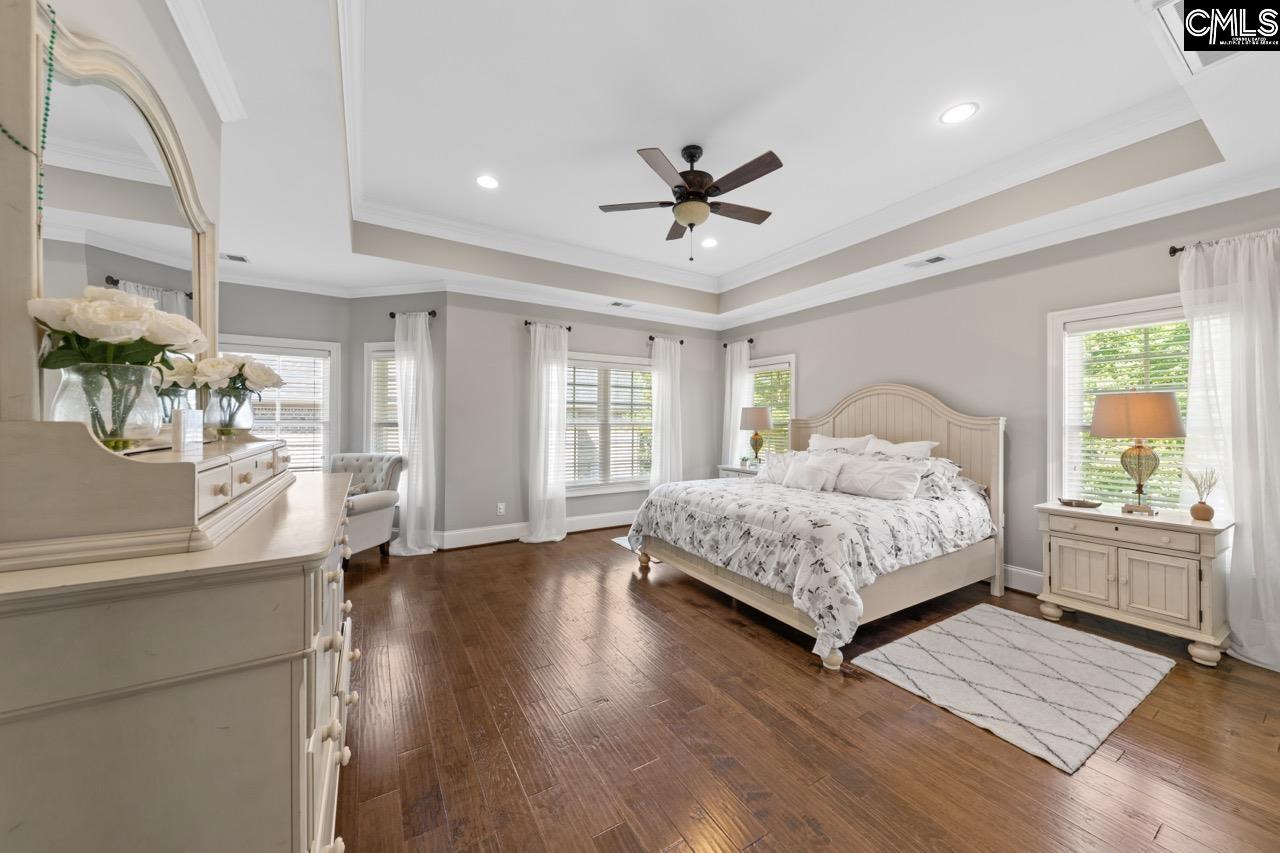 This spacious bedroom features hardwood flooring and abundant natural light from the large windows.
