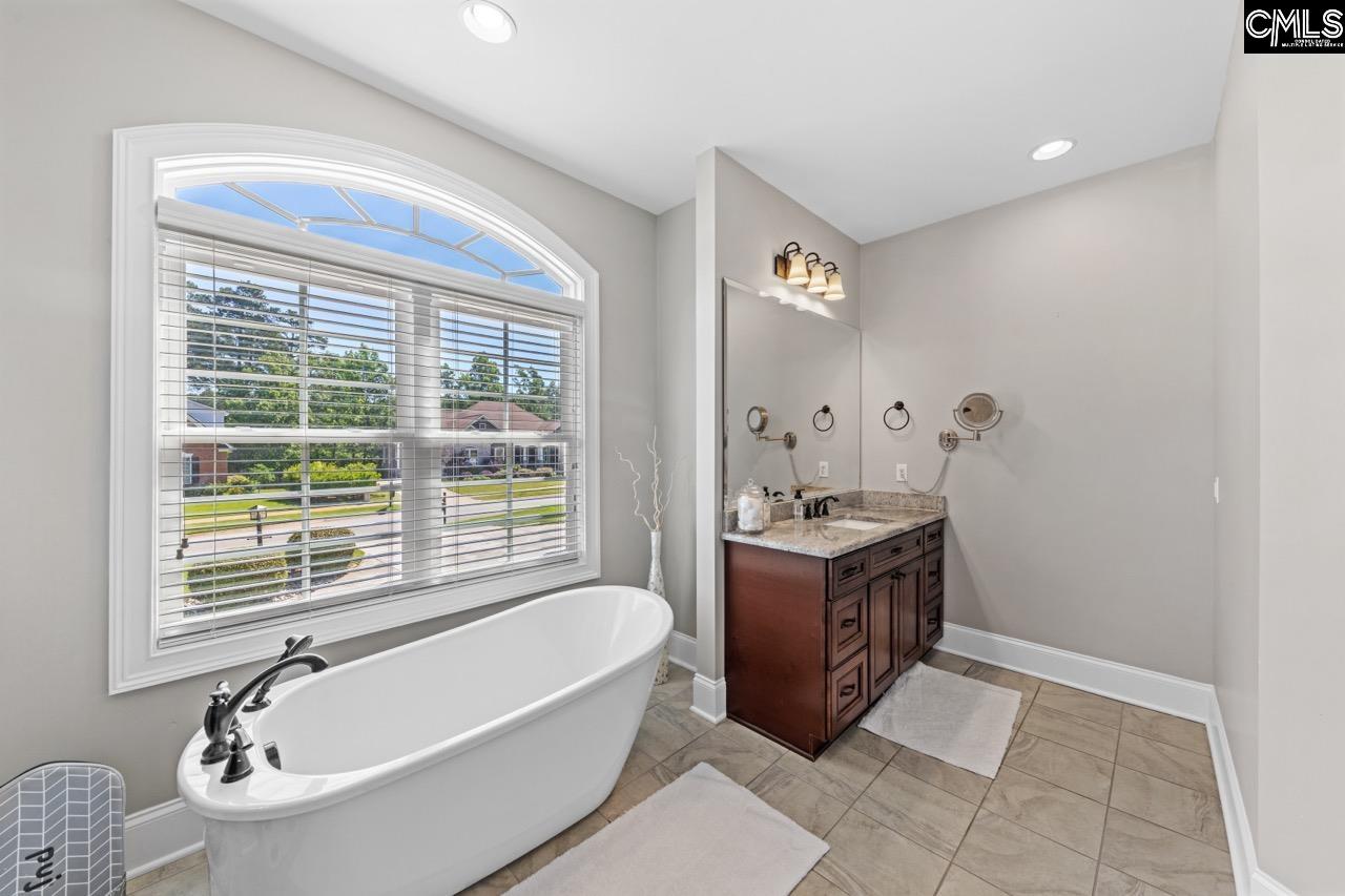 This spacious bathroom features abundant natural light from the large arched window and an elegant v