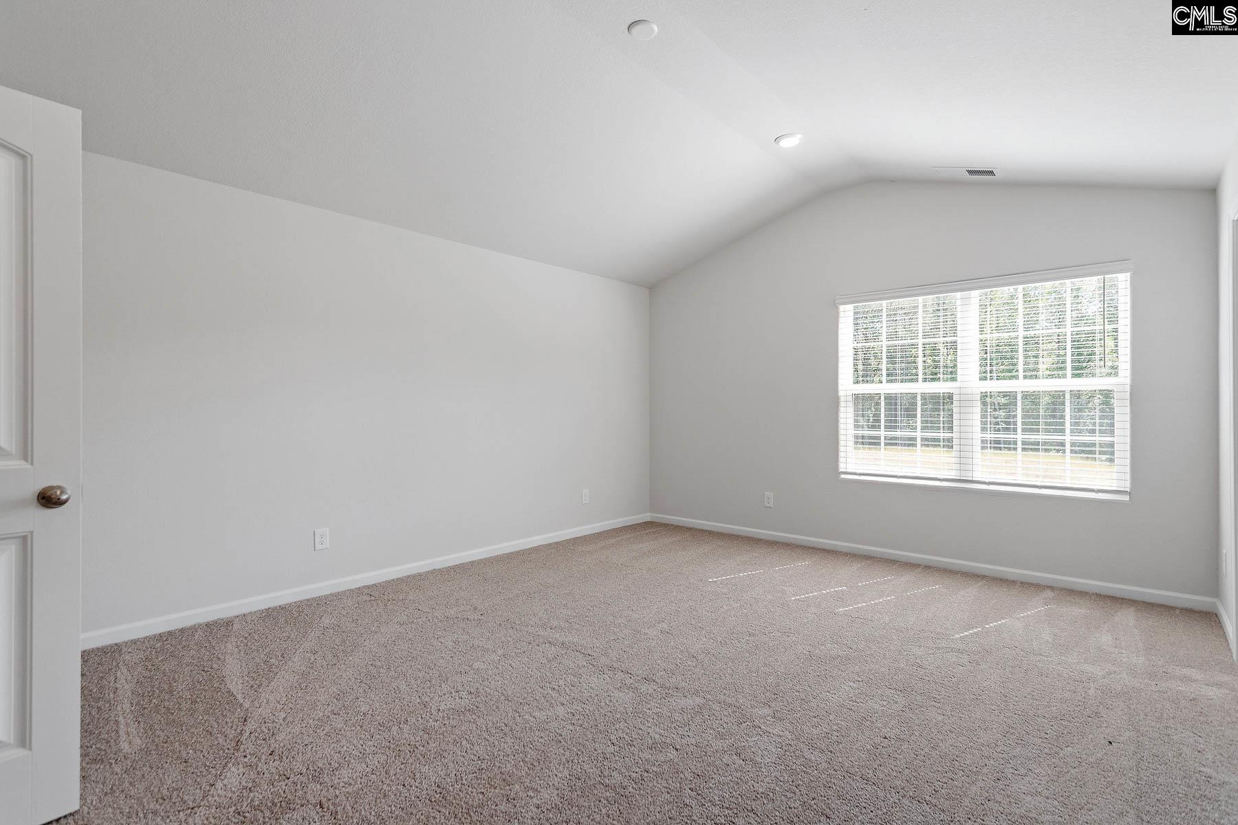 The master bedroom is spacious with a vaulted ceiling and two windows.