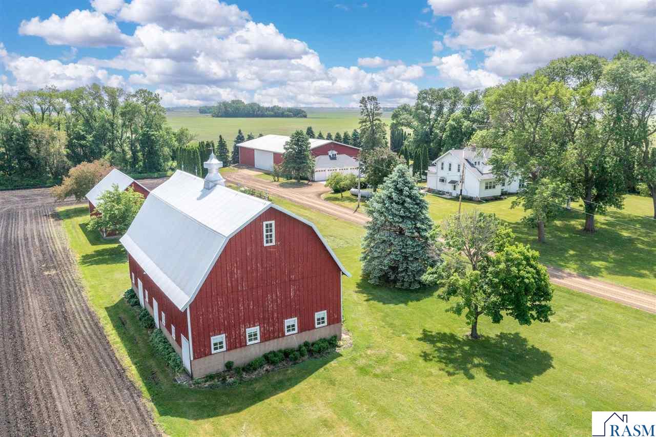 Picture perfect hobby farm with several well-maintained outbuildings, 7.84 acres, 4-stall garage, located just minutes outside of Mankato! This fantastic farmstead has massive room for hobbies of any sort. Horses, livestock, chickens… whatever you can dream up. The classic 2-story displays pride of ownership and is filled with charm, character, and the best features of its day – beautifully trimmed doors and windows, built-ins, original light fixtures, glass doorknobs, stained glass, rooftop open porches, plus modern updates throughout. The stunning Great Room boasts a vaulted ceiling, skylights, multiple patio doors, gas fireplace, and hardwood flooring that flows into the adjoining living room. The eat-in kitchen offers granite countertops, stainless steel appliances, tile backsplash and flooring. You will also find a main floor bedroom, and laundry/mudroom with ¾ bath. Upstairs hosts 3 additional bedrooms, full bath, and den. The lower level is partially finished with an office, family room with exposed brick, storage, mechanicals, and workbench. The paver patio area with pergola and spacious deck is spent sipping lemonade and watching nature! Welcome to your next chapter. There is so much to love here… call today to see this incredible property!