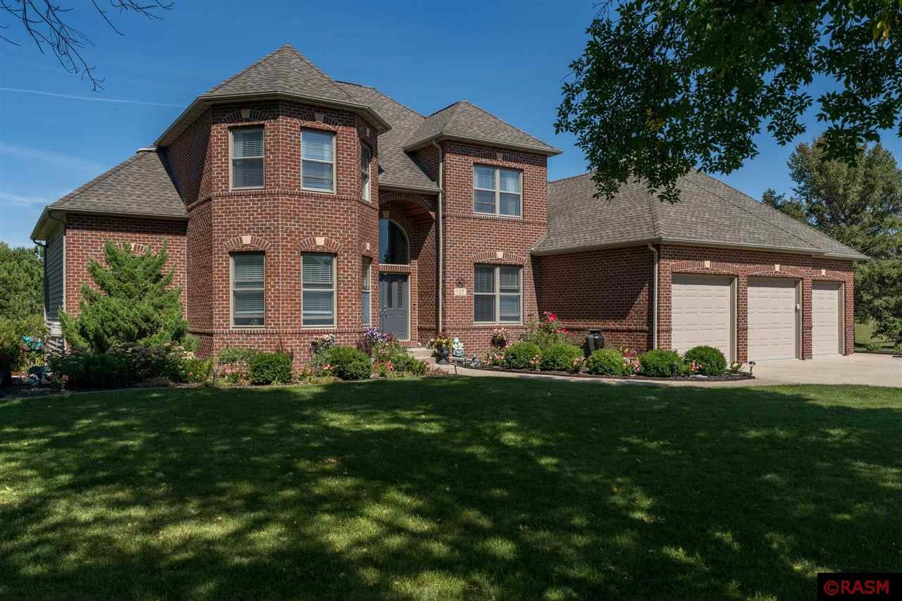 Move-in ready and situated on a beautifully landscaped spacious lot, this immaculate home offers everything you've been dreaming of! Featuring 5 bedrooms, 3 bathrooms, and a 3-stall garage, this property boasts exceptional design details, including elegant arched openings throughout. The well-maintained exterior showcases a large deck, patio, firepit area, inground sprinkler system, and a pet containment system, making it perfect for outdoor enjoyment and relaxation. Step inside the double-door vaulted entry to find an open-concept formal dining room complemented by a 2-sided Kasota stone fireplace, which can be enjoyed from both the great room—complete with a balcony above—and the vaulted living room. The custom kitchen, updated by Cherry Creek in 2021, is a chef’s delight, featuring a center island with seating, pendant lighting, stainless steel appliances, tile flooring, and a breakfast nook with access to a deck and a 3-season screened porch. The primary bedroom suite is a serene retreat, offering a private bathroom with a separate soaker tub, walk-in closet, and a walk-in shower. The main level also includes an office, a laundry room, and a convenient half bath. Upstairs, you'll find three additional spacious bedrooms and a full bathroom, while the lower level provides additional living space, including an open-concept rec room with a wet bar, dining area, and family room featuring a cozy corner gas fireplace. The 5th bedroom, another full bathroom, and a flexible office space—which could also serve as a guest bedroom—complete the lower level. This home is packed with updates for modern living, including a new washer/dryer (2022), HVAC (2020/21), water heater (2020/21), air exchanger (2020/21), septic (2024), and new flooring throughout 90% of the home (2021). Enjoy the energy efficiency of sprayed wall insulation (2020) and the modern ambiance created by LED fixtures and fans. Don't miss this incredible opportunity to make this stunning property your own!