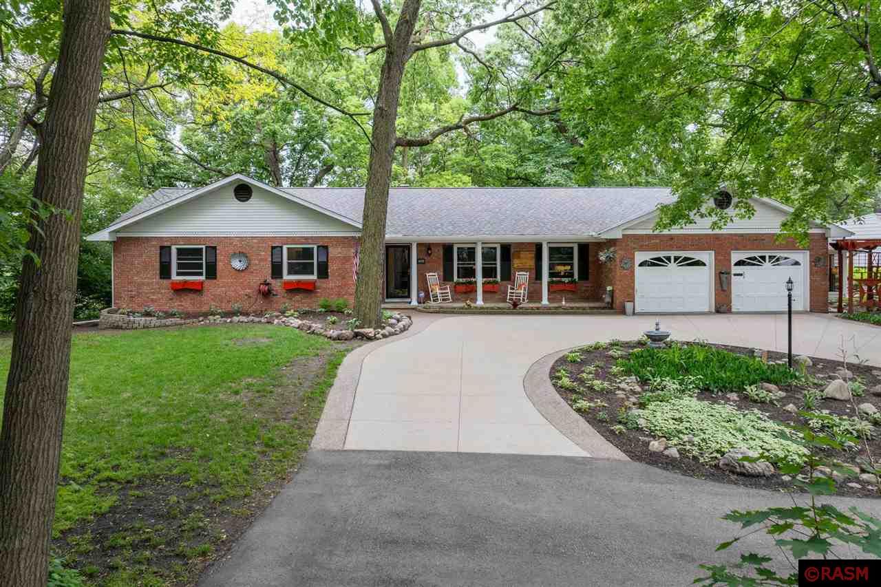 Overlooking the scenic backdrop of Rasmussen Woods, this spacious brick rambler in West Mankato offers the perfect combination of privacy, comfort, and location. The expansive one-level layout features generous room sizes and warm birch woodwork and cabinetry throughout. The main floor includes a formal living room and a welcoming family room complete with floor-to-ceiling built-ins, a wood-burning fireplace, and sliding doors leading to the backyard. The updated kitchen features quartz countertops, a tile backsplash, stainless steel appliances, and dining area with built-ins. All three main-level bedrooms offer double closets, and the primary suite includes a private bath and patio access. Additional main-level highlights include a mudroom and laundry off the garage, a convenient half bath, and a stunning screened porch—ideal for relaxing or entertaining. The lower level adds versatility with a large rec room which includes an egress window making it a potential 5th bedroom, an oversized bedroom, and a workshop. Enjoy peace of mind with numerous updates including a new roof, carpet, updated mechanicals, and much more. This is a rare opportunity to enjoy a private setting with wooded views, all while being close to trails, parks, and everything West Mankato has to offer.