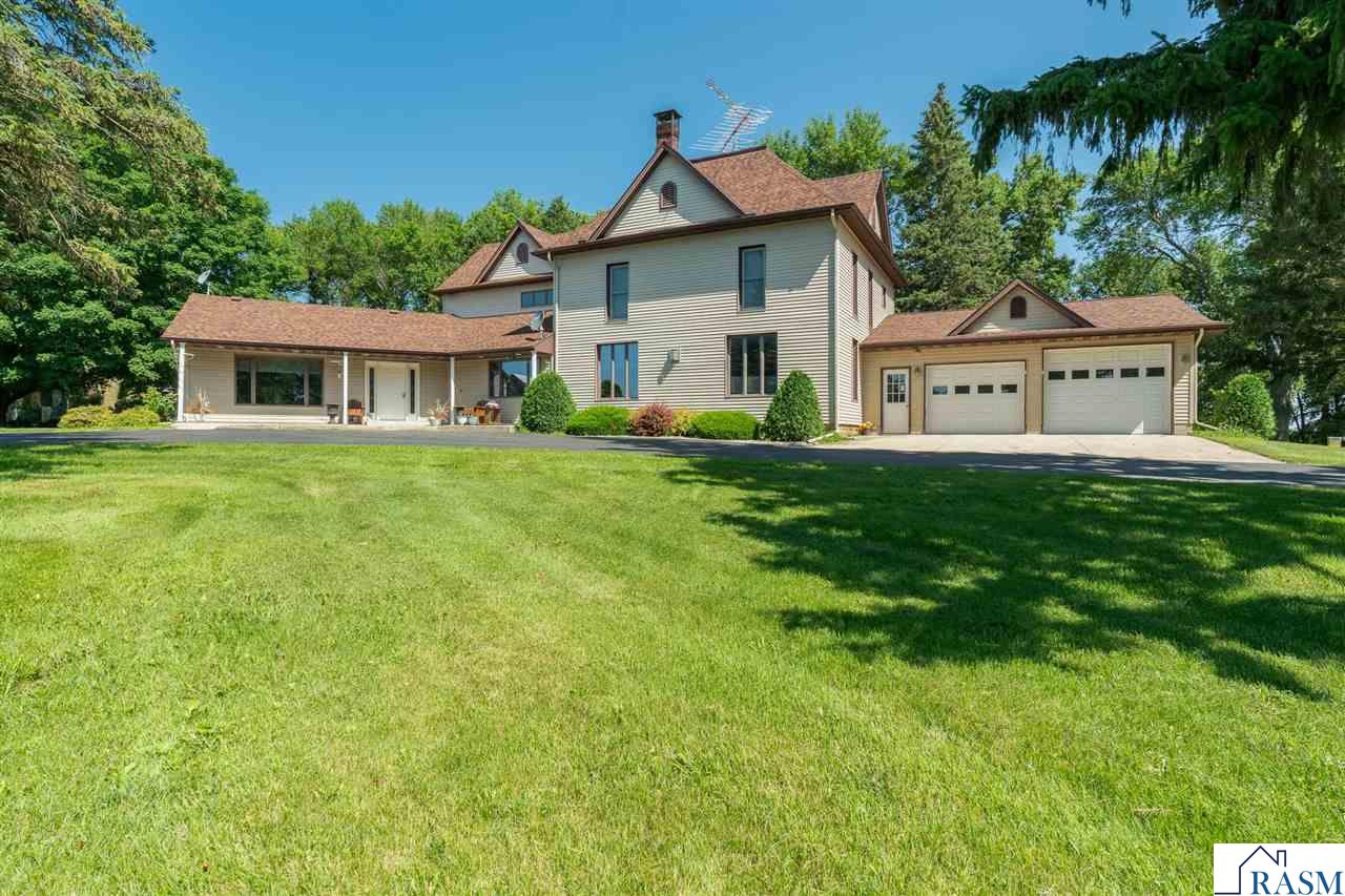 Dreaming of your paradise property?! This is it! Tucked into an absolutely picturesque setting with a tree-lined drive on 8+ acres offering landscaped sitting areas amongst the trees, gardens, and rolling lawn. This sprawling property with over 3800 square feet of living space must be seen to be truly appreciated. A spacious foyer welcomes you; to the left is the main living room w/pellet stove and a 4-season porch that takes you to the backyard. To your right is the dining room, kitchen with large center island w/granite & gas cooktop.  Off the kitchen you access a covered deck, aggregate patio, and a landscaped fire pit. Also on the main floor is a thoughtfully designed laundry room & pantry with ample storage and functionality, 3/4 bath & hot tub room. A craftsman-style living room with brick FP, rustic beams, cabinets & more make this an ideal place for gathering. The main-floor primary bedroom connects to a full bath with separate shower & tub + dual sinks and has a large walk-in closet. Head on up the main stair case and the 2nd floor brings 3 additional bedrooms, a full bath, and two rooms of closets and space for a playroom/craft area/reading nook...endless options to utilize it! Above the kitchen is the 5th bedroom (or nifty game room and bar) with 1/2 bath. The attached garage is heated with a 3rd overhead stall, great for toy storage, plus a framed out area that is currently used for workout space. A 45' x 72' shop with concrete floors and automatic overhead doors is perfect for just about any set-up.  This includes finished space for a heated workshop, and open space for vehicle/equipment storage.  A barn and granary (both with steel roofs) are a sign of the property's history, and are in nice condition. Add a paved basketball court, garden, patio, gorgeous views all around, and you've got your dream site! With compliant septic and numerous updates throughout, including steel siding, new 50-year roof (with transferable warranty) on the house, steel roofs on the outbuildings (2023), new pressure tank in well (2024), solid doors throughout the house, you'll appreciate the care that has gone into this property.