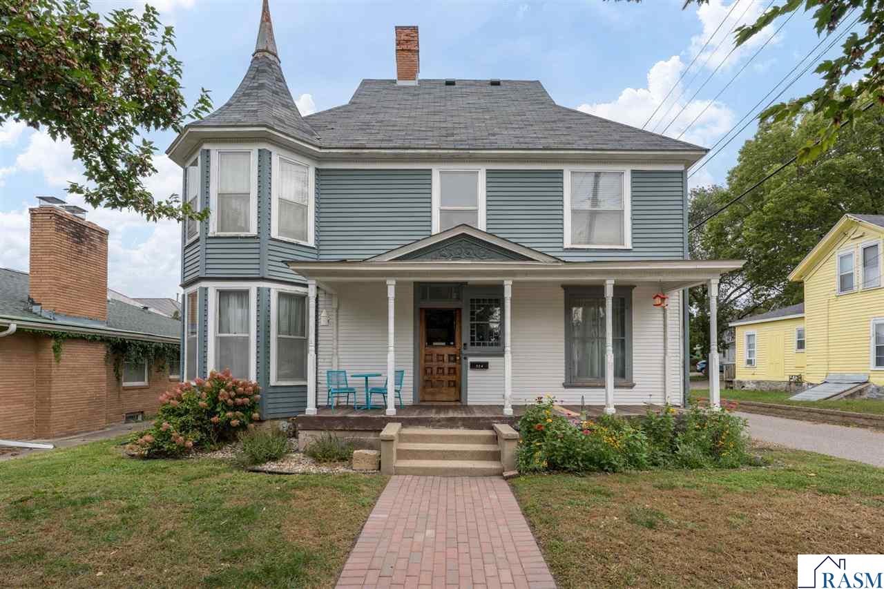 Discover timeless elegance with modern comfort in this beautifully renovated Queen Anne-style home in historic downtown Mankato. Showcasing original Victorian details—beautiful hardwood floors, 9-foot ceilings, bay windows, and original woodwork—this residence seamlessly blends old-world character with thoughtful updates. The updated kitchen features stainless steel appliances, a butcher block island with sink, refreshed cabinetry, and a stylish tile backsplash. A back entrance off of the kitchen provides convenient access to private parking for two full-sized vehicles. On the main level, you’ll also find a full bathroom, a formal dining room accented by an antique coal-burning fireplace (non-functional), and a charming second living room—once the home’s library—separated by original pocket doors. Upstairs offers four generously sized bedrooms, including one currently designed as a convenient laundry room with balcony access. A beautifully updated full bathroom and a walk-up attic with potential for third-floor living space complete the upper level. Recent updates include a radon mitigation system (2023), new water heater (2023), updated electrical breaker box (2024), staircase carpet runner (2025), and HVAC system (2017). This home truly captures the best of both worlds—historic character and modern amenities conveniently located in the downtown district.